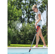 Une femme nettoie une piscine avec un aspirateur de piscine à manche.