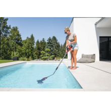 Femme nettoie piscine avec aspirateur de piscine