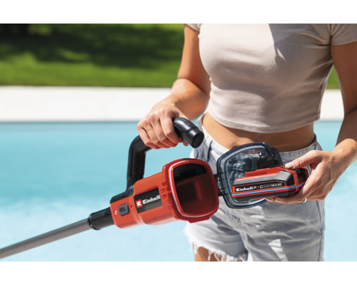 Une femme insère une batterie Einhell dans un coupe-bordure