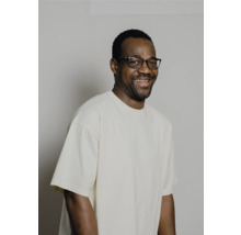 Portrait d'un homme souriant avec des lunettes et un t-shirt