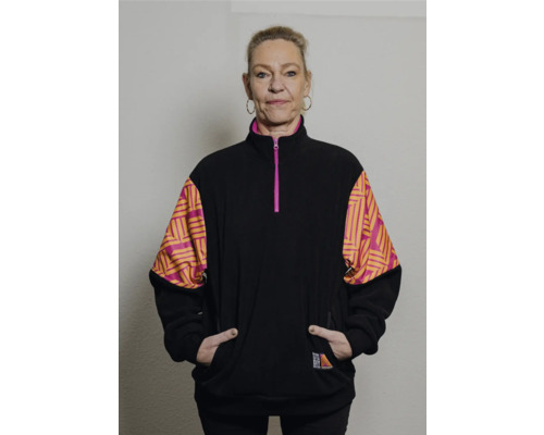 Femme portant une veste polaire noire avec des motifs géométriques sur les manches.