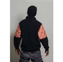 Vue arrière d'une personne portant un bonnet et une veste polaire noire à manches à motifs, ainsi qu'un pantalon de travail gris.