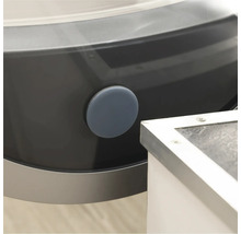 Detailansicht einer Waschmaschine mit einem runden, grauen Verschlussstopfen