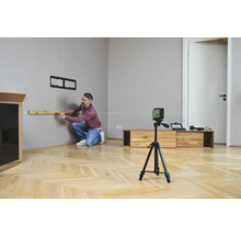 Un homme utilise un niveau laser pour aligner une étagère sur un mur