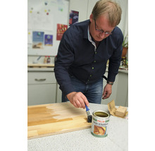 Un homme applique du vernis pour bateaux et yachts sur une planche de bois