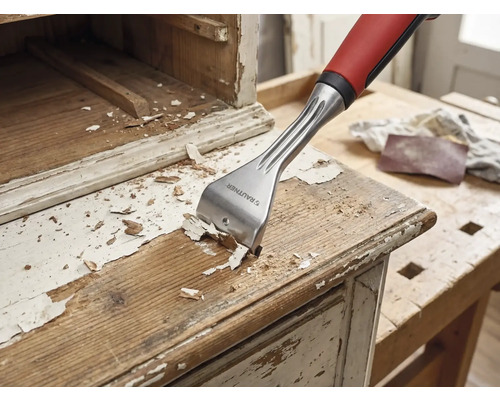 Racloir à bois en train d'enlever de la peinture d'un meuble en bois