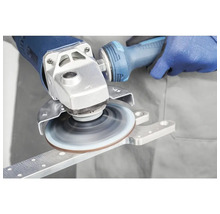 Meuleuse d'angle traitant une pièce métallique avec un disque abrasif rotatif.
