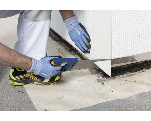 Ein Handwerker sägt eine Dämmplatte mit einer Handsäge zu.