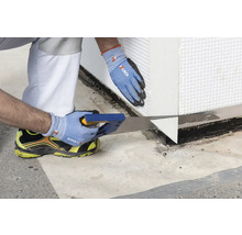 Mann sägt Dämmstoffplatte mit Handsäge