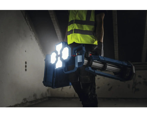 Artisan portant un projecteur de chantier