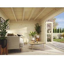 Vue intérieure d'une maison de jardin en bois avec canapé, plantes et porte ouverte sur le jardin