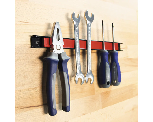 Outils tels que pince, clés et tournevis sur une barre à outils magnétique.