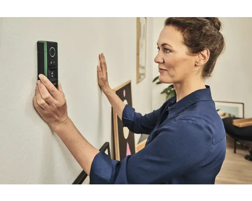 Femme utilisant un scanner mural pour localiser des objets dans un mur