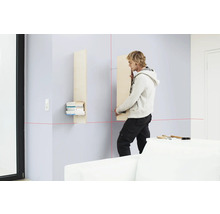 Un homme installe une étagère murale à l'aide d'un laser