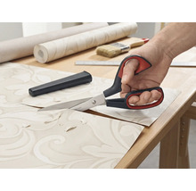 Des ciseaux à papier peint coupent du papier peint sur une table.