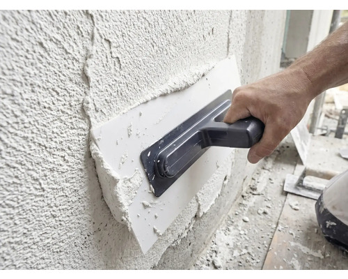 Un artisan applique de l'enduit sur un mur à l'aide d'une taloche.
