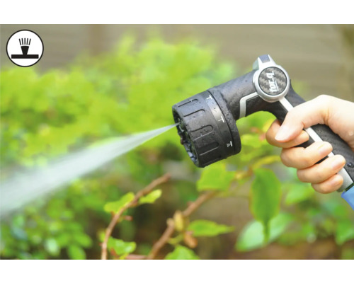 Main tenant un pistolet d'arrosage de tuyau d'arrosage pendant l'arrosage des plantes