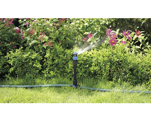 Gartenszene mit Rasensprenger, der Pflanzen bewässert