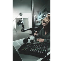 Femme répare une caméra avec un jeu de tournevis dans un atelier