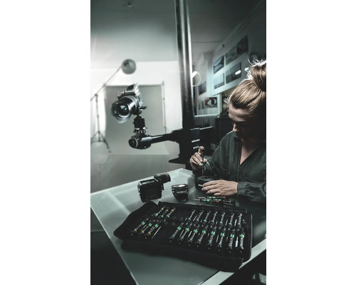 Femme répare une caméra avec un jeu de tournevis dans un atelier