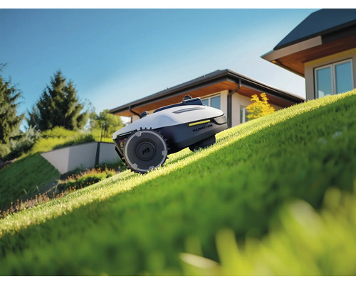 Robot tondeuse sur une pelouse devant une maison.