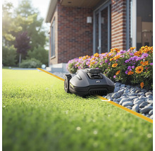 Tondeuse robot sur pelouse devant la maison