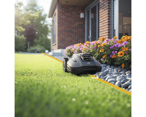 Tondeuse robot sur pelouse devant la maison