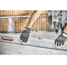 Une personne qui aligne un mur de briques avec un niveau à bulle et des gants de travail