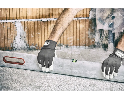 Une personne qui aligne un mur de briques avec un niveau à bulle et des gants de travail