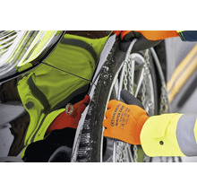 Montage von Schneeketten am Reifen eines Autos mit Handschuhen.