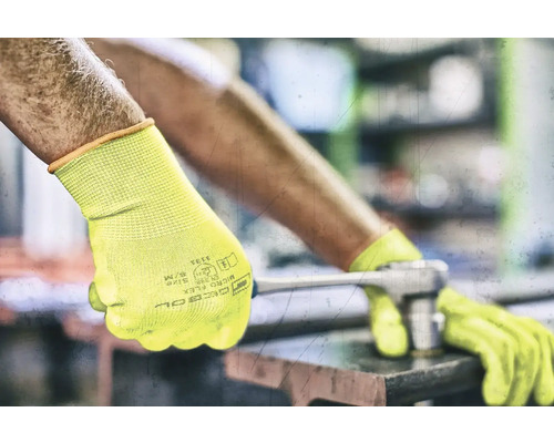 Un homme portant des gants de travail jaunes utilise une clé à molette.