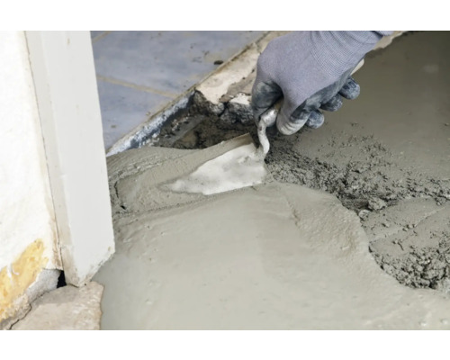 Handwerker glättet Ausgleichsmasse mit einer Glättkelle.