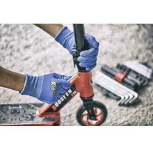 Une personne répare une trottinette avec des outils et des gants de protection