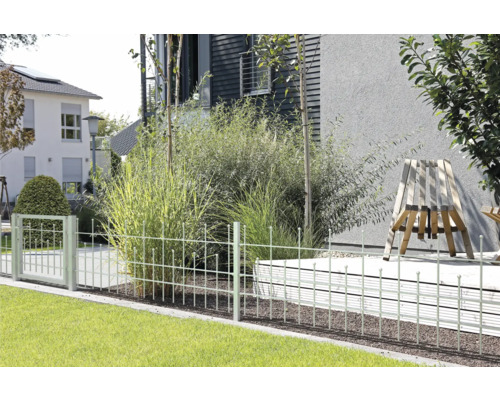 Gartenszene mit einem Metallzaun, Gras und Pflanzen