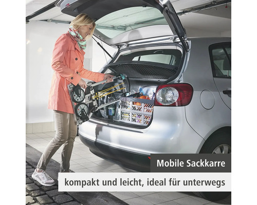 Frau lädt eine mobile Sackkarre in das Heck eines Autos