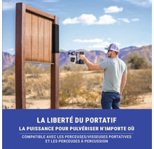 Un homme utilise un pulvérisateur de peinture sur un objet en bois à l'extérieur.