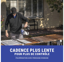 Une personne pulvérise de la peinture avec un pulvérisateur de peinture sur des portes d'armoires en bois.