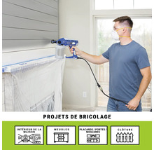 Un homme utilise un pulvérisateur de peinture à l'intérieur pour des projets de bricolage