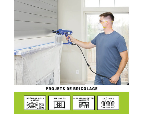 Un homme utilise un pulvérisateur de peinture à l'intérieur pour des projets de bricolage