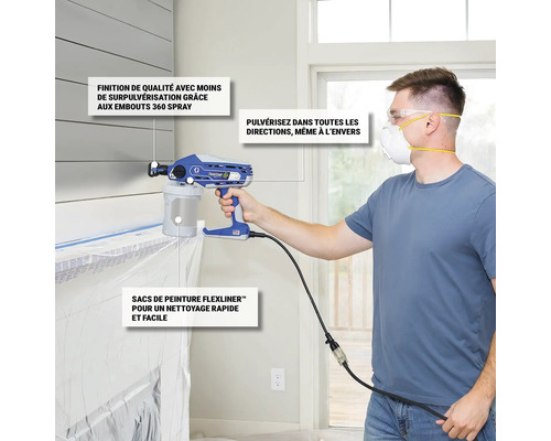 Un homme utilise un pulvérisateur de peinture Graco avec un masque et des lunettes de protection