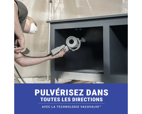 Une personne utilise un pistolet à peinture pour laquer un meuble.