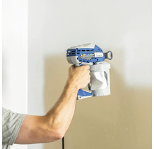 Une personne tient un pistolet à peinture devant un mur