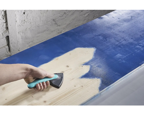 Une personne utilise un répartiteur de peinture pour appliquer de la peinture sur du bois