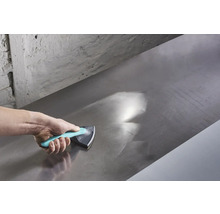 La main utilise une cale à poncer pour lisser une surface métallique.