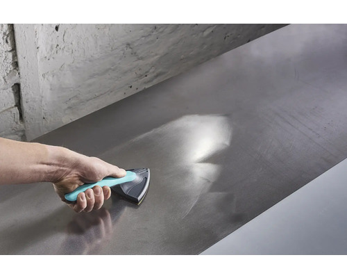 La main utilise une cale à poncer pour lisser une surface métallique.