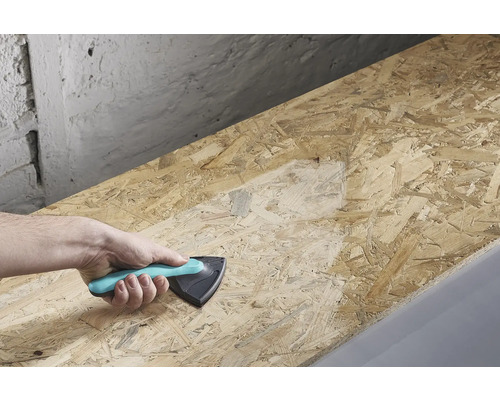 Une main tient une cale de ponçage et ponce une planche de bois.