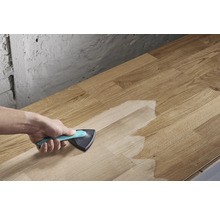 Une personne applique un traitement de surface à l'aide d'un pinceau triangulaire sur une planche de bois.