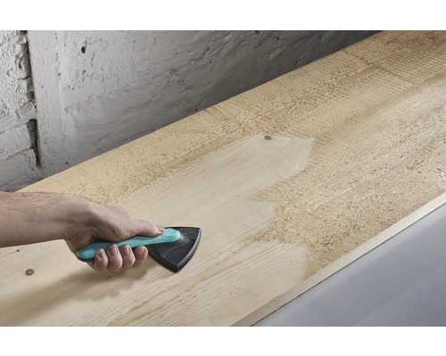 Main ponçant une planche en bois avec une ponceuse triangulaire