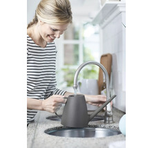 Femme remplissant un arrosoir gris à un robinet