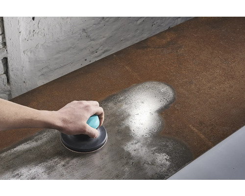 Ponceuse manuelle en cours d'utilisation sur une surface métallique